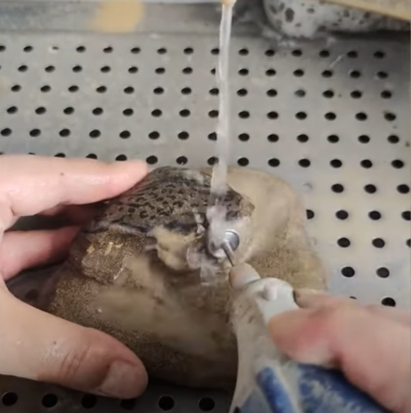 Water pouring over rock while artist carves with a tool