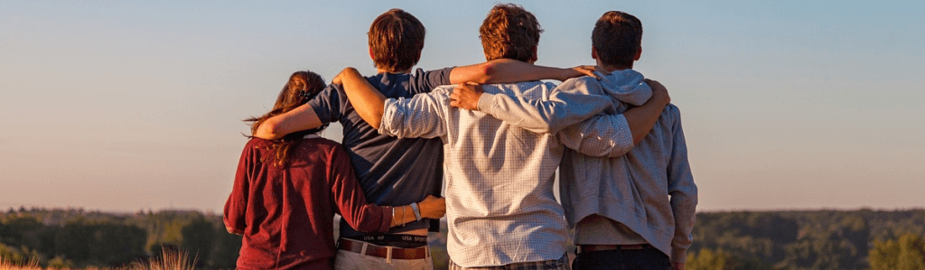 A group of young people put their arms around each other in acceptance.
