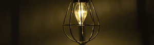Image of a dimly lit bulb in a wire frame cage.